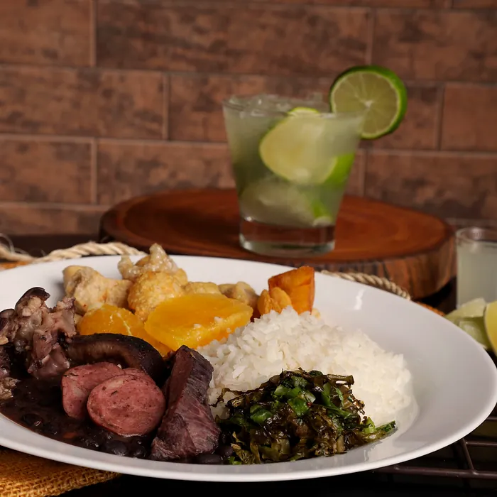 Prato de feijoada completa com caipirinha